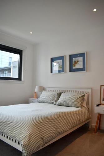 a white bedroom with a bed and a window at Private room and bathroom in shared flat with parking in Glasgow