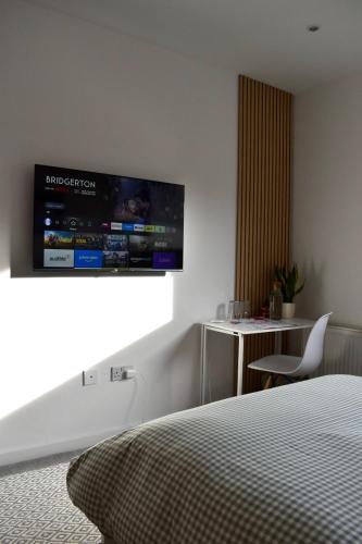 a bedroom with a bed and a television on the wall at Private room and bathroom in shared flat with parking in Glasgow