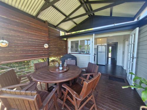 an outdoor patio with a wooden table and chairs at Tweed River Waterfront Cottage in Murwillumbah
