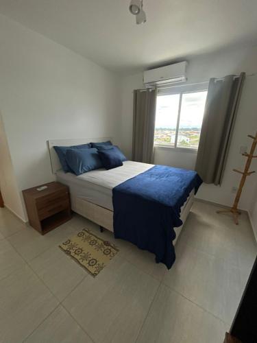 a bedroom with a bed with blue pillows and a window at Cantinho da Lyah in Torres