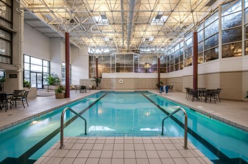 a pool in a building with tables and chairs at Crowne Plaza Chicago Ohare Hotel & Conf Ctr by IHG in Rosemont