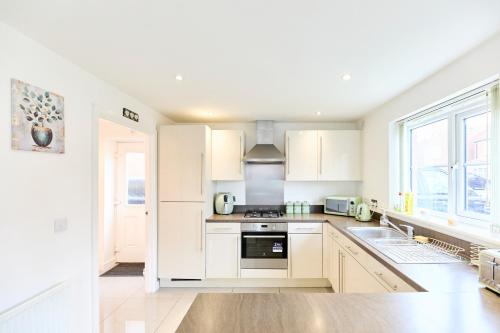 a kitchen with white cabinets and a sink at Lavish Lodge - Perfect for couples, families and contractors! in Wakefield