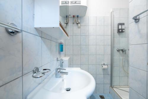 a white bathroom with a sink and a shower at COY Apartments Leoben - Central near Uni & Station with 24 7 Check-in in Leoben