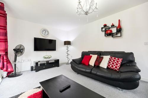 a living room with a black leather couch and a tv at Lavish Lodge - Perfect for couples, families and contractors! in Wakefield