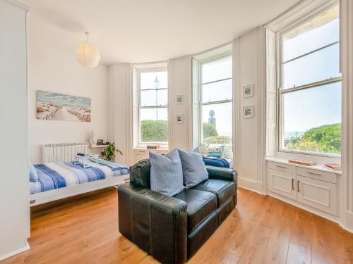 a living room with a leather couch and two windows at The Beach Studio in Brighton & Hove
