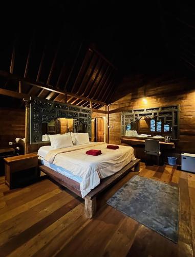 a bedroom with a large bed and a desk at Penginapan Gelar in Jembrana