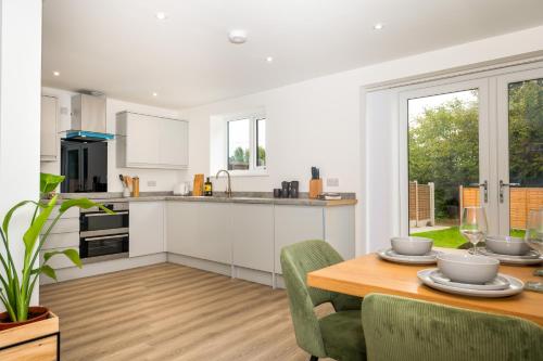 a kitchen and dining room with a table and chairs at Brand New 3-Bed House - Walk to Stone Town Centre! in Stone