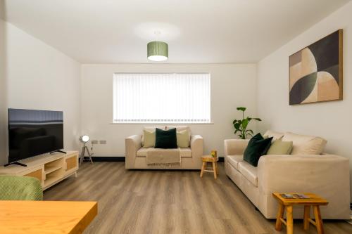 a living room with a couch and a tv at Brand New 3-Bed House - Walk to Stone Town Centre! in Stone