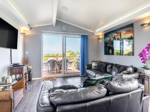 a living room with a leather couch and a balcony at Tranquillity in Dinas