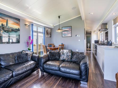 a living room with two leather couches and a kitchen at Tranquillity in Dinas
