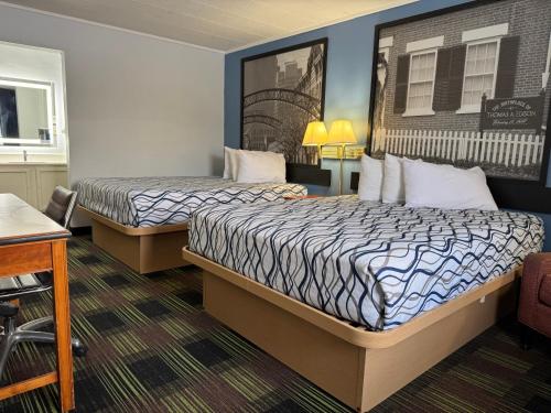 a hotel room with two beds and a desk at Sprucewood Inn in Elyria