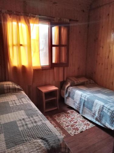 a bedroom with two beds and a window at Cabañas Soledad in Villa Giardino