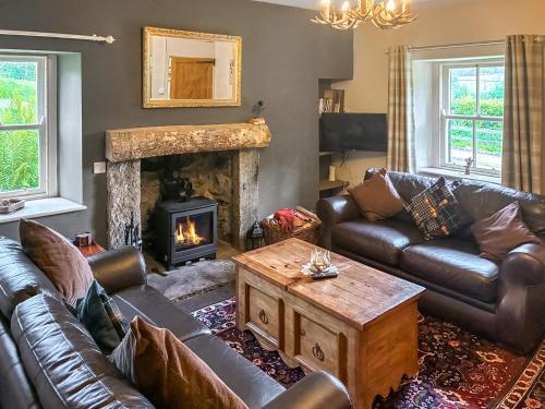 a living room with leather furniture and a fireplace at Professors Cottage in Girvan