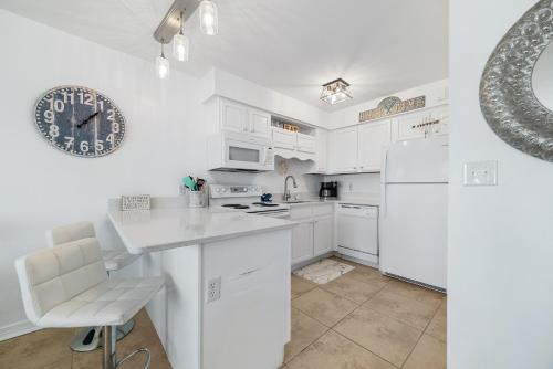 a kitchen with white cabinets and a clock on the wall at Perdido Skye 64 in Pensacola