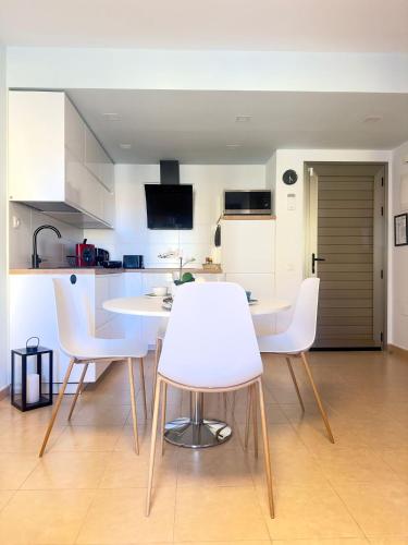 a kitchen with a table and white chairs in it at NextGen Dimora Luna I Private Garden & Pool Fuerteventura in Costa de Antigua