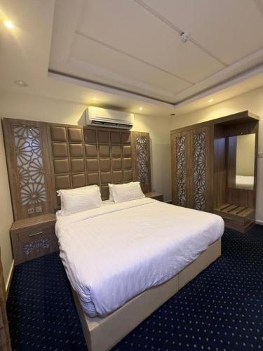 a bedroom with a large bed with white sheets at شاليهات وشقق ليالي رهيف in Abha