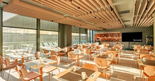a restaurant with tables and chairs and windows at Sercotel Barcelona El Prat in El Prat de Llobregat