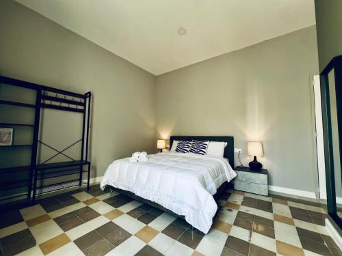 a bedroom with a bed and a checkered floor at Turretta Stay - Private Room with Ensuite Bathroom in Vittoriosa, Three Cities in Birgu