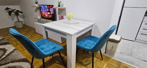 a white table with blue chairs in a living room at Apartman Panorama 2 in Požarevac