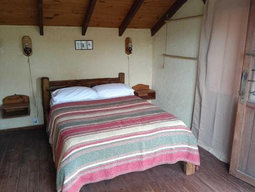 a bedroom with a large bed with a striped blanket at Búho Multiespacio in Villa Giardino