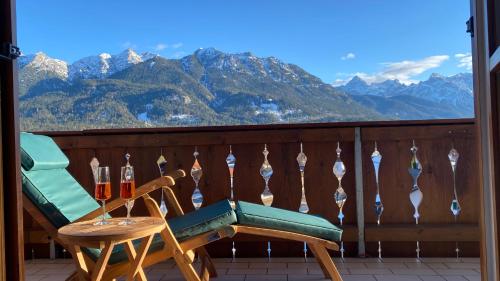a balcony with two chairs and a table with wine glasses at Apartment Sonnenhang in Wallgau