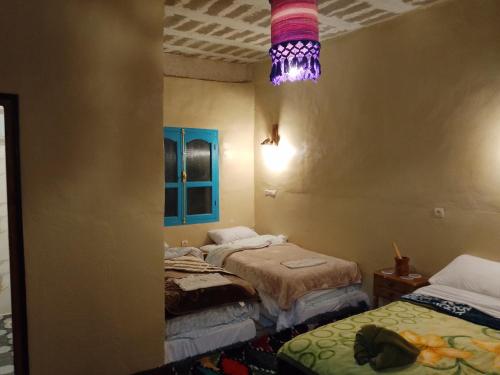 a room with two beds and a purple light at Gîte Palma Eagle Ziz Canyon in Er Rachidia