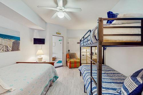 a bedroom with two bunk beds and a ceiling fan at SB50 Saltwater Sanctuary in Sunset Beach