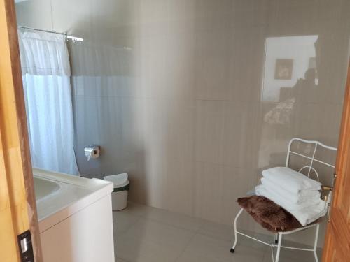 a white bathroom with a shower and a chair at Regreso al Encanto in Puyehue