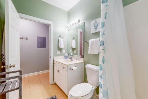a bathroom with a toilet and a sink and a mirror at SB72 Sea Trail Golf-Beach Condo in Sunset Beach