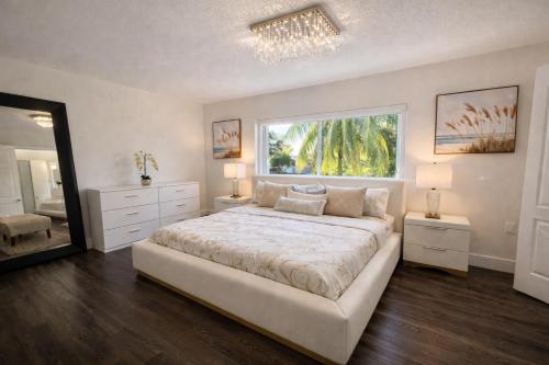 a white bedroom with a large bed and a window at Villa Miami Lakes 2 in Hialeah