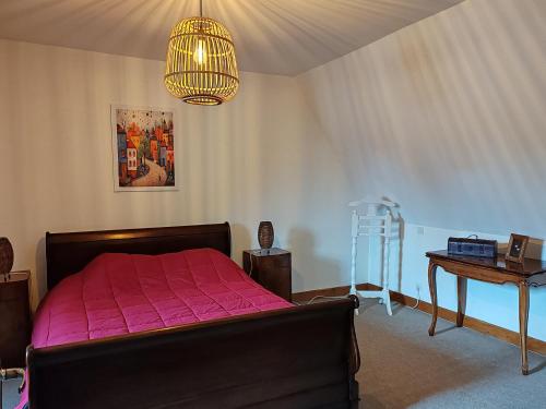 a bedroom with a bed and a table and a chandelier at Les colombages bis in Pazayac