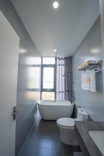 a white bathroom with a tub and a toilet at Loc Binh Hotel in Thôn Phú An