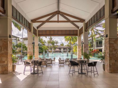 a lobby with tables and chairs and a swimming pool at Pullman Port Douglas Sea Temple Resort and Spa in Port Douglas
