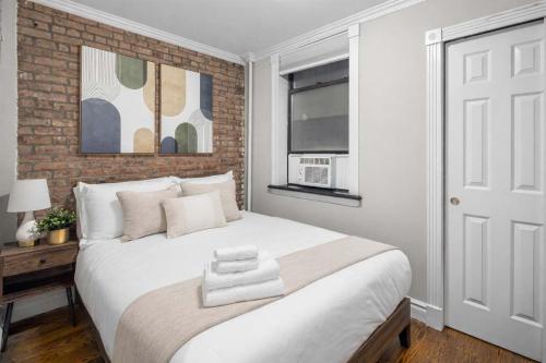 a bedroom with a white bed and a brick wall at Trendy East Village Escape in New York