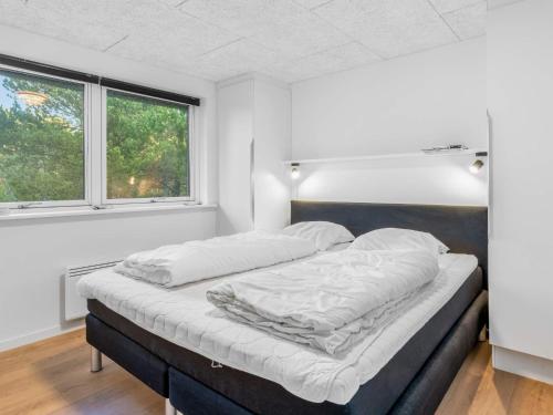 a bed in a room with two windows at 5 star holiday home in Rømø in Toftum