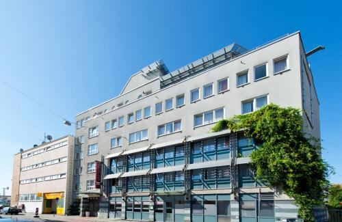 a tall white building with a tree in front of it at Leonardo Hotel Nürnberg in Nuremberg