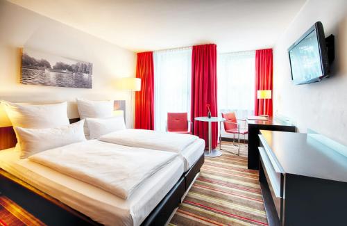 a hotel room with a bed and a desk at Leonardo Hotel München City West in Munich