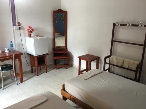 a bedroom with a bed and a desk and a mirror at Gnaanams Hotel and Restaurant in Jaffna