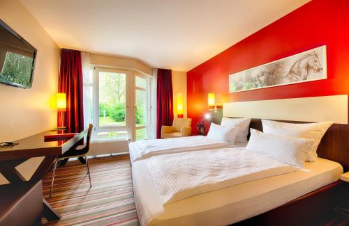 a hotel room with a large bed and a desk at Leonardo Hotel München City West in Munich