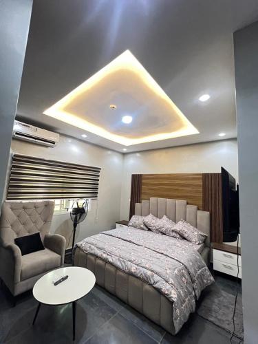 a bedroom with a bed and a couch and a table at Shortlet247 in Hausa
