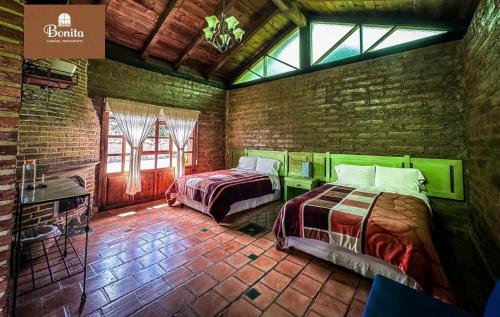 a bedroom with two beds and a brick wall at Quinta Bonita in Zacatlán