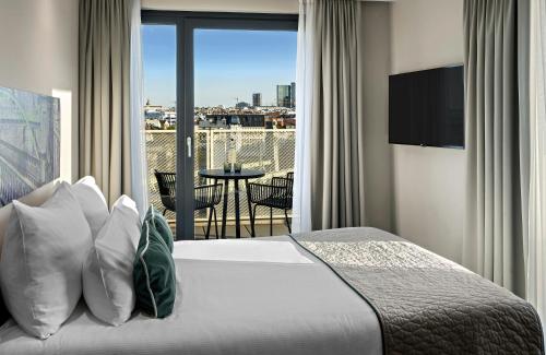 a bedroom with a bed and a balcony with a view at Leonardo Hotel Vienna City West in Vienna