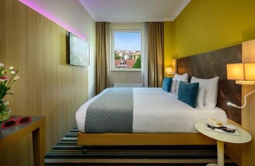 a hotel room with a bed and a window at Leonardo Hotel Budapest in Budapest