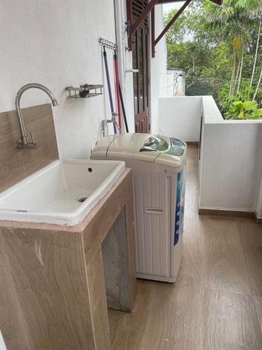 a bathroom with a sink and a trash can at The Teak Ambalangoda in Ambalangoda