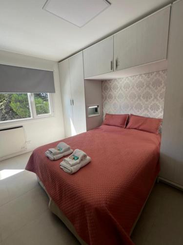 a bedroom with a red bed with two towels on it at Las Maras Apart. in Rada Tilly