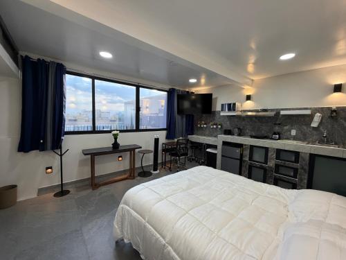 a bedroom with a large white bed and a kitchen at Juárez new studio city view full equipment in Mexico City