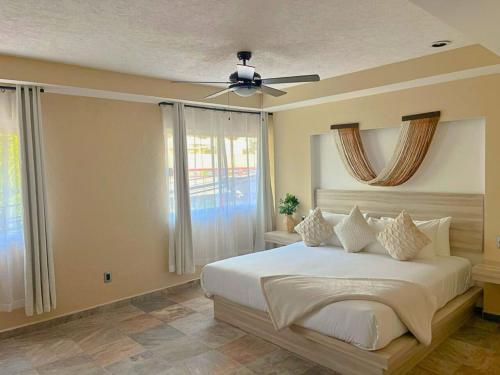 a bedroom with a white bed with a ceiling fan at Quinta Nina Playa del Carmen - Solo Adultos in Playa del Carmen