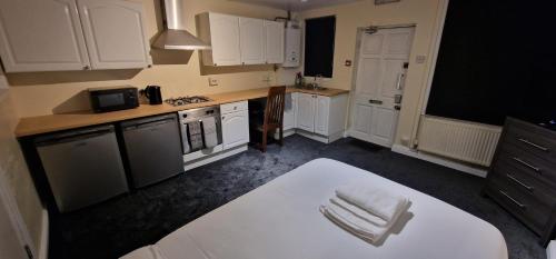 a kitchen with white cabinets and a white chair in it at SELF CHECK-IN QUICK ROOMz WAKEFIELD in Wakefield