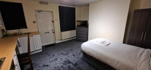 a bedroom with a bed and a kitchen with a sink at SELF CHECK-IN QUICK ROOMz WAKEFIELD in Wakefield