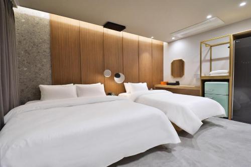 two beds in a hotel room with white sheets at 통영 하운드호텔 죽림점 in Naejuk-to